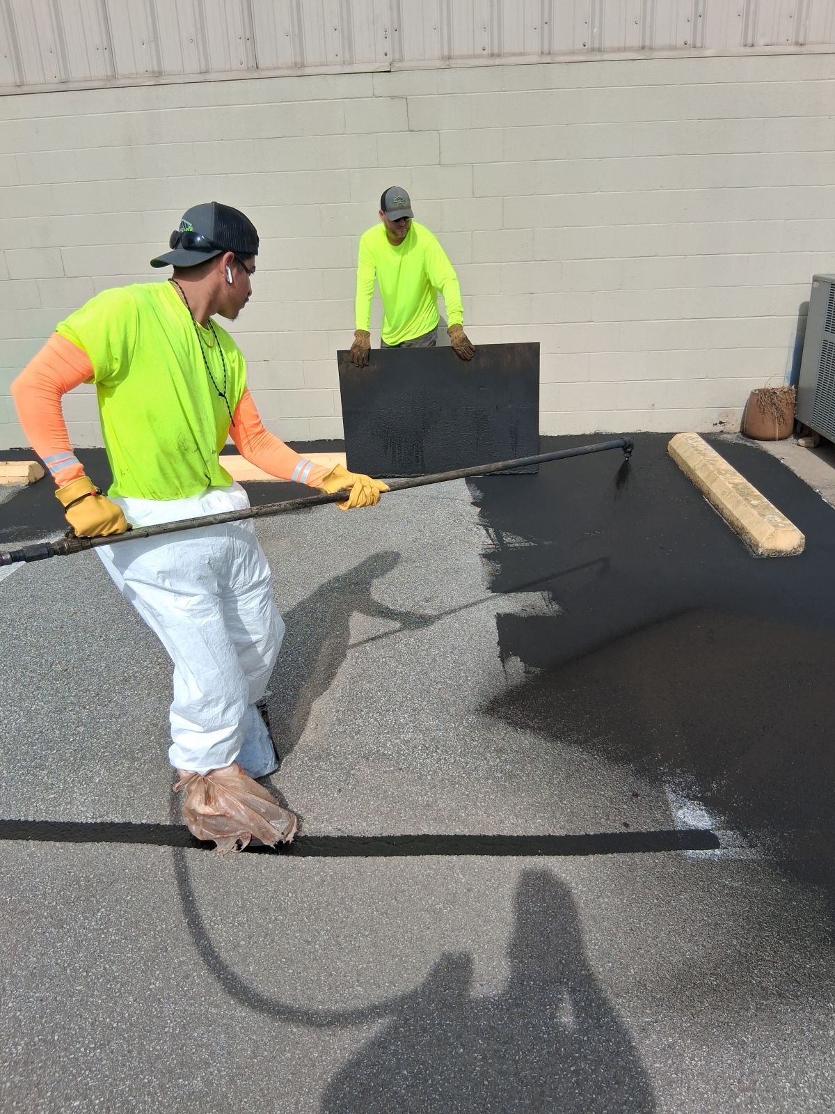 Parking Lots Plus team applying sealcoating